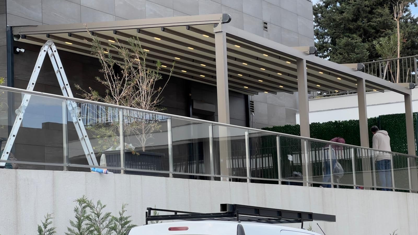 Teras üzerine kurulmuş motorlu pergola tente; gergin kumaş örtü ve profillere gömülü LED aydınlatma.